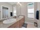 Bright bathroom featuring double sinks with granite countertop, a large mirror, and wood cabinets at 10808 Alico Pass, New Port Richey, FL 34655