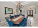 A refined dining room with large table and blue chairs next to decorative arched doorway and chandelier at 10808 Alico Pass, New Port Richey, FL 34655