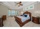 Comfortable primary bedroom with tray ceiling, sitting area, and bright windows at 10808 Alico Pass, New Port Richey, FL 34655