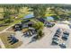 Aerial view of a golf course clubhouse featuring cart parking, a full parking lot, and a serene pond at 11254 Mollymawk Ct, New Port Richey, FL 34654
