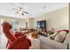 Bright living room with tile flooring, comfortable seating, a ceiling fan, and a large television at 11254 Mollymawk Ct, New Port Richey, FL 34654