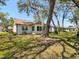 Backyard view of the home featuring mature trees and green lawn at 11536 Golden Rain Dr, New Port Richey, FL 34654