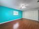 A spacious bedroom with hardwood floors, ceiling fan, closet, and light blue accent wall at 11648 Boynton Ln # 39Gb, New Port Richey, FL 34654