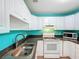 Bright kitchen featuring white cabinets, black countertops, stainless steel sink and appliances at 11648 Boynton Ln # 39Gb, New Port Richey, FL 34654