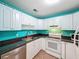 Bright kitchen featuring white cabinets, black countertops, stainless steel sink and appliances at 11648 Boynton Ln # 39Gb, New Port Richey, FL 34654
