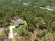 An aerial view shows a home set on a wooded lot in a scenic neighborhood, with mature trees all around at 11730 Hawks Nest Trl, Brooksville, FL 34614