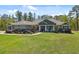 Charming home with lush landscaping, mature trees, and rocking chairs on the front porch at 11730 Hawks Nest Trl, Brooksville, FL 34614