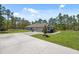 View of home with large driveway, two car garage, and manicured lawn with shrubs at 11730 Hawks Nest Trl, Brooksville, FL 34614