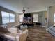 Open living room features wood-look flooring, modern furniture, ceiling fan, and a wall-mounted television at 11796 Crestridge Loop, New Port Richey, FL 34655