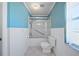 Bright bathroom featuring blue walls, white wainscoting, and a shower-tub combo for a fresh, clean aesthetic at 1216 Yawl Way, Venice, FL 34285