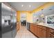 Open kitchen featuring stainless steel refrigerator, granite countertops, and wood cabinetry at 1216 Yawl Way, Venice, FL 34285