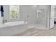 The luxurious bathroom features a soaking tub, a walk-in shower, and sleek tile for a spa-like experience at 12617 Wetmore Ct, Odessa, FL 33556