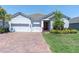 Welcoming single-story home with a brick driveway, three-car garage, and professionally landscaped front yard at 12617 Wetmore Ct, Odessa, FL 33556