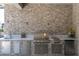 Outdoor kitchen with a built-in grill, sink, and stone backsplash at 12617 Wetmore Ct, Odessa, FL 33556