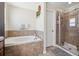 Well-lit bathroom featuring a soaking tub and a glass-enclosed shower at 18331 Waydale Loop, Hudson, FL 34667
