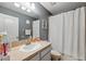 Neutral bathroom features gray walls, a large mirror, and a shower with a white patterned curtain at 18331 Waydale Loop, Hudson, FL 34667