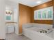 Bathroom featuring a large soaking tub with tiled surround, shuttered window, and adjacent toilet room at 18663 Autumn Lake Blvd, Hudson, FL 34667
