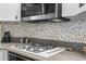 Close-up shot of gas stovetop with custom tile backsplash and range hood at 18663 Autumn Lake Blvd, Hudson, FL 34667