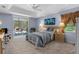 Bright main bedroom featuring a king bed, neutral carpet, slider to a screened patio, and ensuite bath at 18663 Autumn Lake Blvd, Hudson, FL 34667