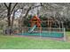 Fenced-in community playground with slide and swings surrounded by mature shade trees and greenery at 18663 Autumn Lake Blvd, Hudson, FL 34667