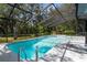 Screened in pool with a small waterfall feature and mature trees adding privacy at 18663 Autumn Lake Blvd, Hudson, FL 34667
