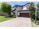 Charming two-story home featuring a stone facade, a dark brown two car garage, and landscaped front yard at 2431 Murray Pass, Odessa, FL 33556