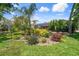 Lush backyard landscaping with mature trees and colorful flowering bushes and a screened lanai at 2924 Windridge Dr, Holiday, FL 34691