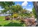A beautifully landscaped backyard with colorful plants and lush trees overlooks a serene lake at 2924 Windridge Dr, Holiday, FL 34691