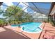 Relax by the sparkling in-ground pool surrounded by a screened enclosure and lush greenery at 2924 Windridge Dr, Holiday, FL 34691