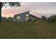 Backyard view of a home with a screened patio and spacious lawn at dusk at 312 Barrington Ct, Spring Hill, FL 34609