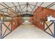 Barn interior featuring stalls along either side of a concrete pathway and a light and airy ceiling at 3431 Saturn Rd, Brooksville, FL 34604