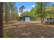 Exterior view of a blue barn, set among trees and an open field, with parking area at 3431 Saturn Rd, Brooksville, FL 34604