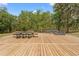 Expansive wood deck featuring dining, lounging, and grill, perfect for outdoor gatherings surrounded by a natural landscape at 3431 Saturn Rd, Brooksville, FL 34604
