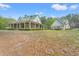 Charming country estate with a wrap-around porch and lush landscaping surrounded by tall trees on a sunny day at 3431 Saturn Rd, Brooksville, FL 34604