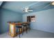 This is a beautiful blue indoor bar area with metal and wood bar, stools, and ceiling fan at 4321 High Ridge Ave, Spring Hill, FL 34609
