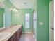 Bathroom with dual sinks, wood cabinets, walk-in shower, and soft green walls at 4321 High Ridge Ave, Spring Hill, FL 34609