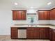 Kitchen featuring wood cabinetry, stainless steel dishwasher, and a double sink under a window at 4321 High Ridge Ave, Spring Hill, FL 34609