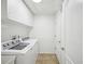 Bright laundry room features a washer, a dryer, storage cabinets, and tiled flooring for easy cleaning and functionality at 4321 High Ridge Ave, Spring Hill, FL 34609
