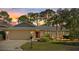 Home at sunset featuring a manicured lawn, mature trees, and an attached two-car garage at 4504 Dewey Dr, New Port Richey, FL 34652