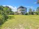The exterior elevation showcases the lush lawn surrounding the elevated home with a spacious backyard at 4514 Fishman Ave, Weeki Wachee, FL 34607