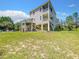 The exterior elevation showcases the lush lawn surrounding the elevated home with a spacious backyard at 4514 Fishman Ave, Weeki Wachee, FL 34607