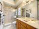 Bright bathroom with a glass-enclosed shower, wooden vanity, large mirror, and neutral tile flooring at 4514 Fishman Ave, Weeki Wachee, FL 34607