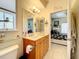 Well-lit bathroom with a wooden vanity, tri-fold mirror, adjacent bedroom view, and tile flooring at 4514 Fishman Ave, Weeki Wachee, FL 34607