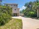 Charming stilt home boasts a circular driveway, boat parking and mature trees, set against a sunny, blue sky at 4514 Fishman Ave, Weeki Wachee, FL 34607