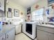 Functional laundry room with a washer, dryer, sink, gray cabinets, and various wall decorations at 4514 Fishman Ave, Weeki Wachee, FL 34607