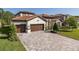 Charming two-story home with a red tile roof, three-car garage, paver driveway, and manicured landscaping at 5070 Night Star Trl, Odessa, FL 33556