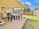 Covered patio with an outdoor dining set overlooking the fenced yard and a large palm tree at 5128 Perennial Dr, Holiday, FL 34690