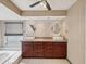 Bathroom with dual sinks, cherry-tone cabinets, a tiled backsplash, and a large garden tub under a window at 5411 Joyner Ave, Spring Hill, FL 34608
