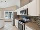 Modern kitchen with stainless steel appliances, mosaic backsplash, and a window view of the pool at 5411 Joyner Ave, Spring Hill, FL 34608