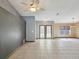 Open living room with tile flooring, neutral paint, ceiling fan and double doors leading to the exterior at 5411 Joyner Ave, Spring Hill, FL 34608